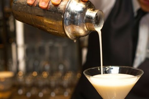 Bartender pouring a cocktail into a Martini glass